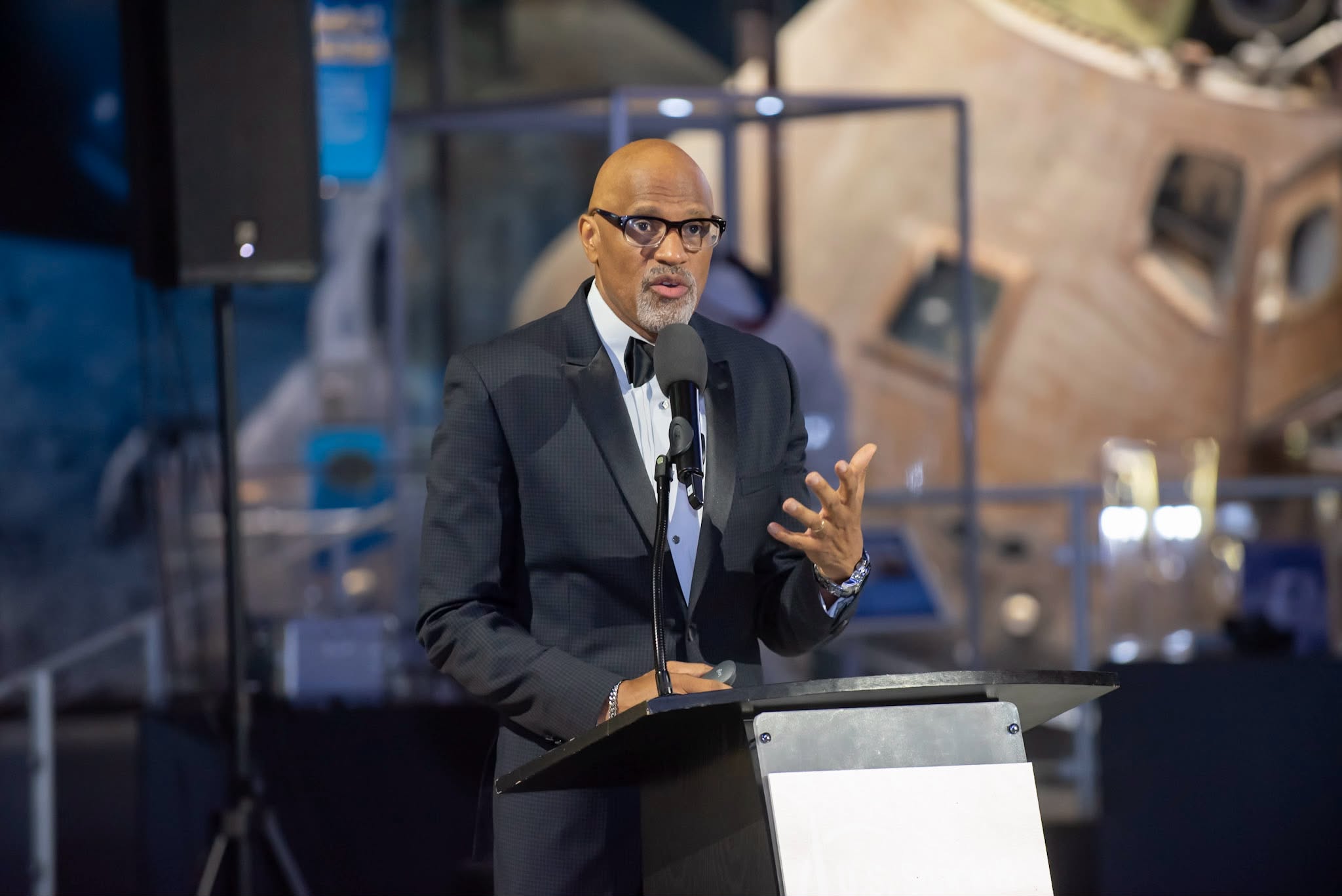 Dr. Nos delivering a keynote at a lectern