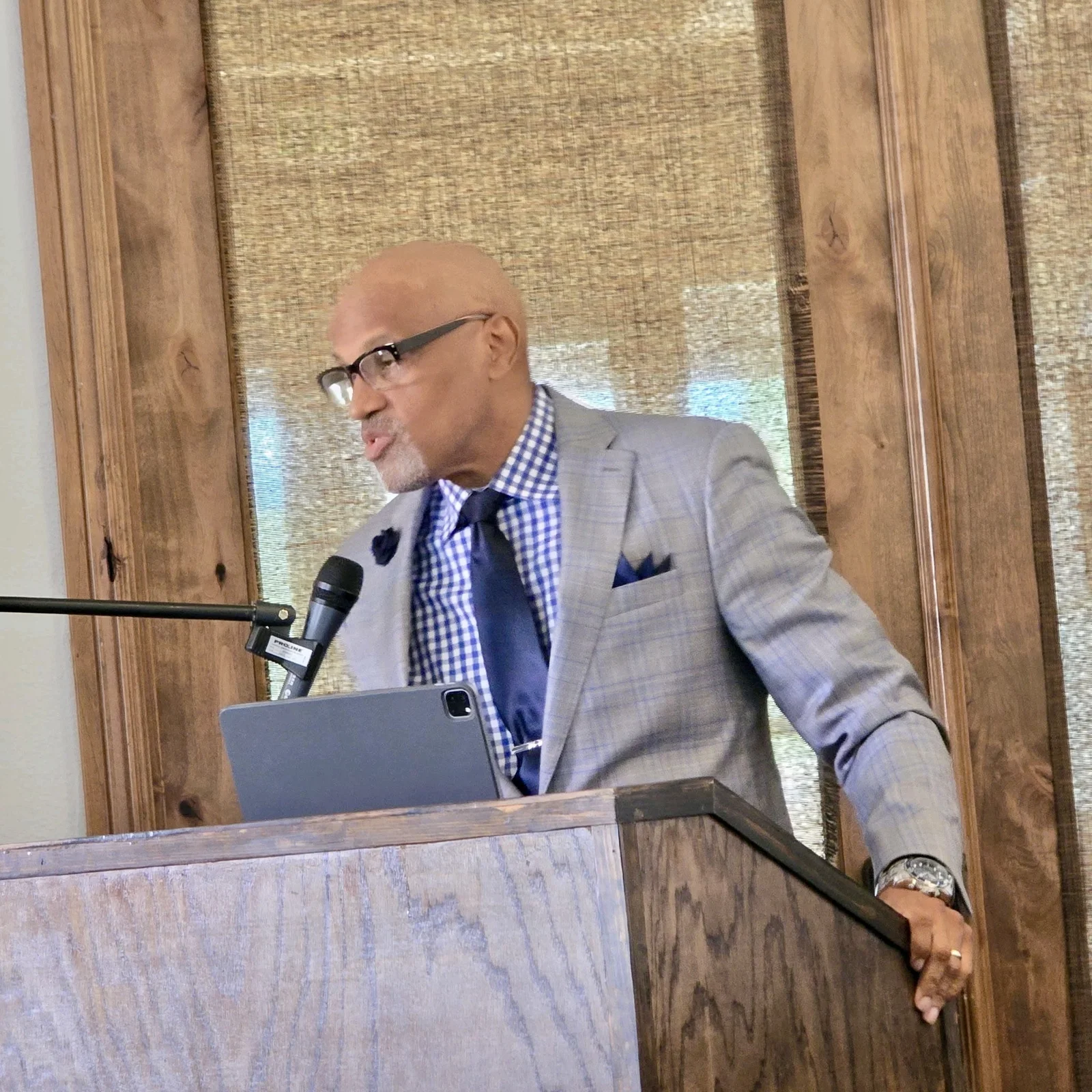 Dr. Nos addressing an audience from a wooden lectern